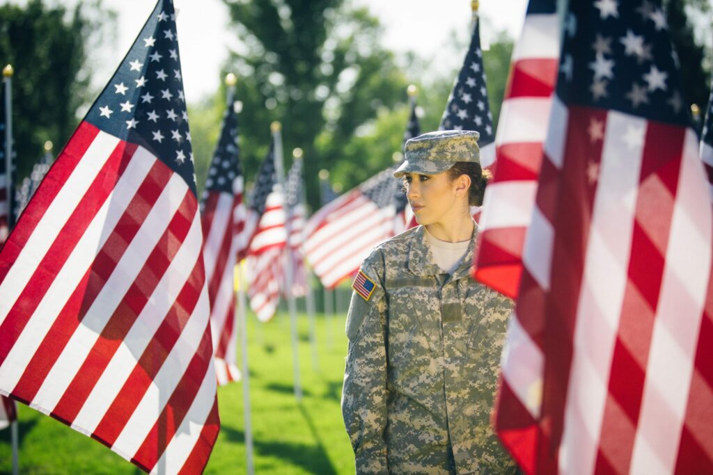 Female soldier standing in field filled with American flags